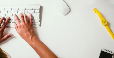 Hands typing on a white keyboard